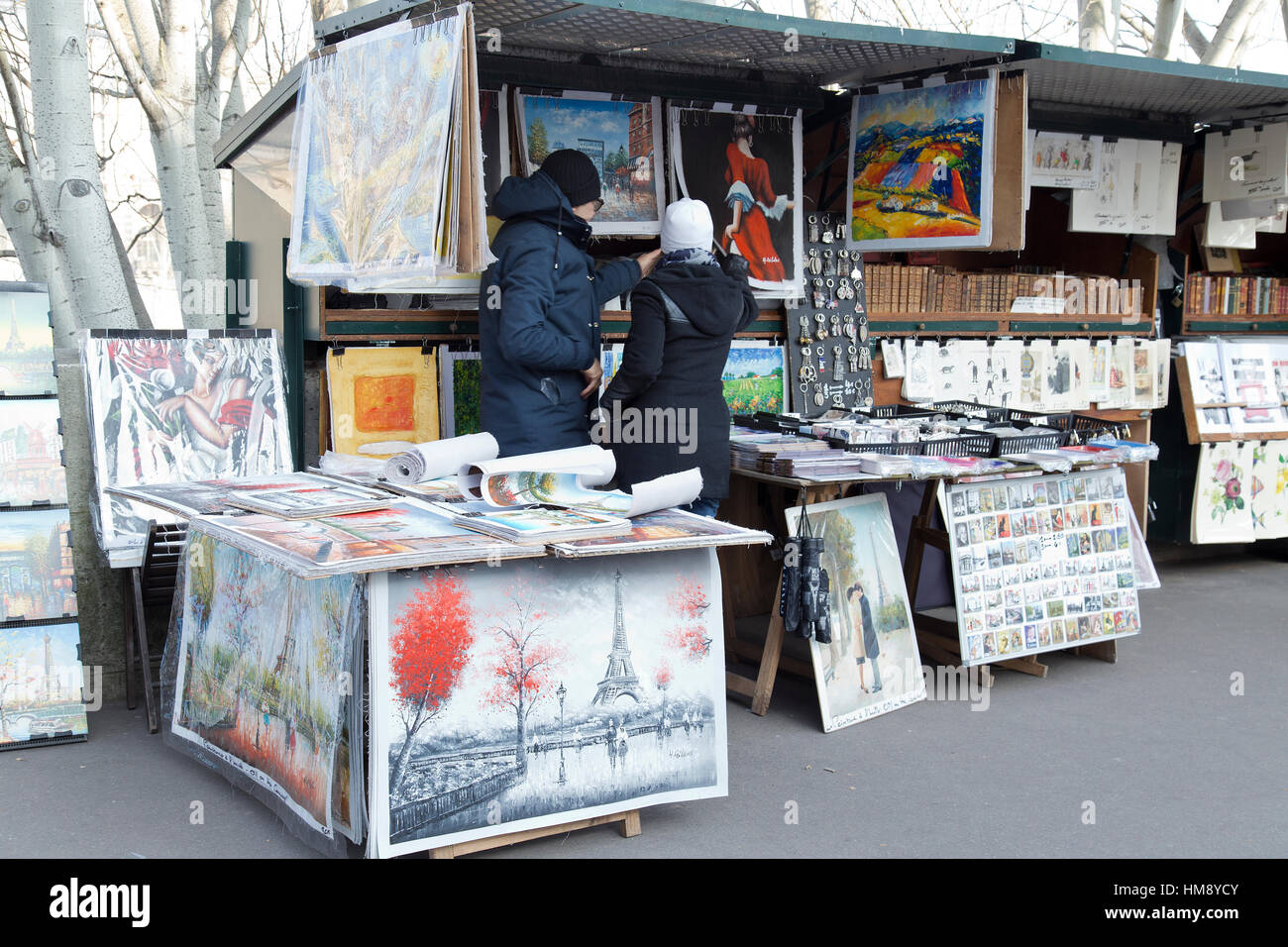 I turisti sfoglia stampa stallo del mercato lungo il Fiume Senna a Parigi in inverno Foto Stock