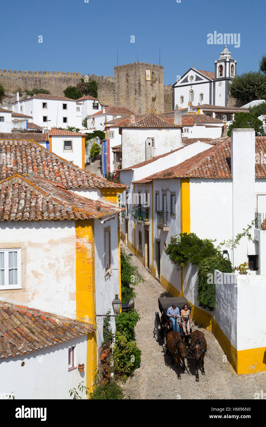 Carro trainato da cavalli e panoramica della città con il castello medievale in background, Obidos, Portogallo Foto Stock
