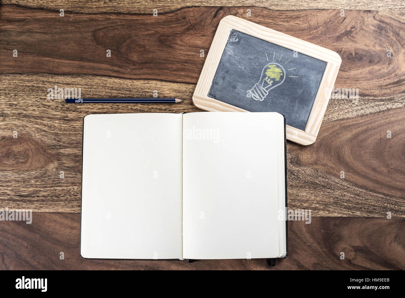 Aprire plain pagina vuota notebook con matita e lampadina della luce sulla lavagna su tavola in legno rustico Foto Stock