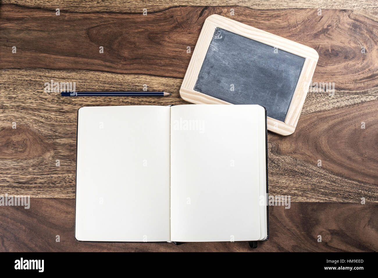 Aprire plain pagina vuota notebook con matita e lavagna su tavola in legno rustico Foto Stock