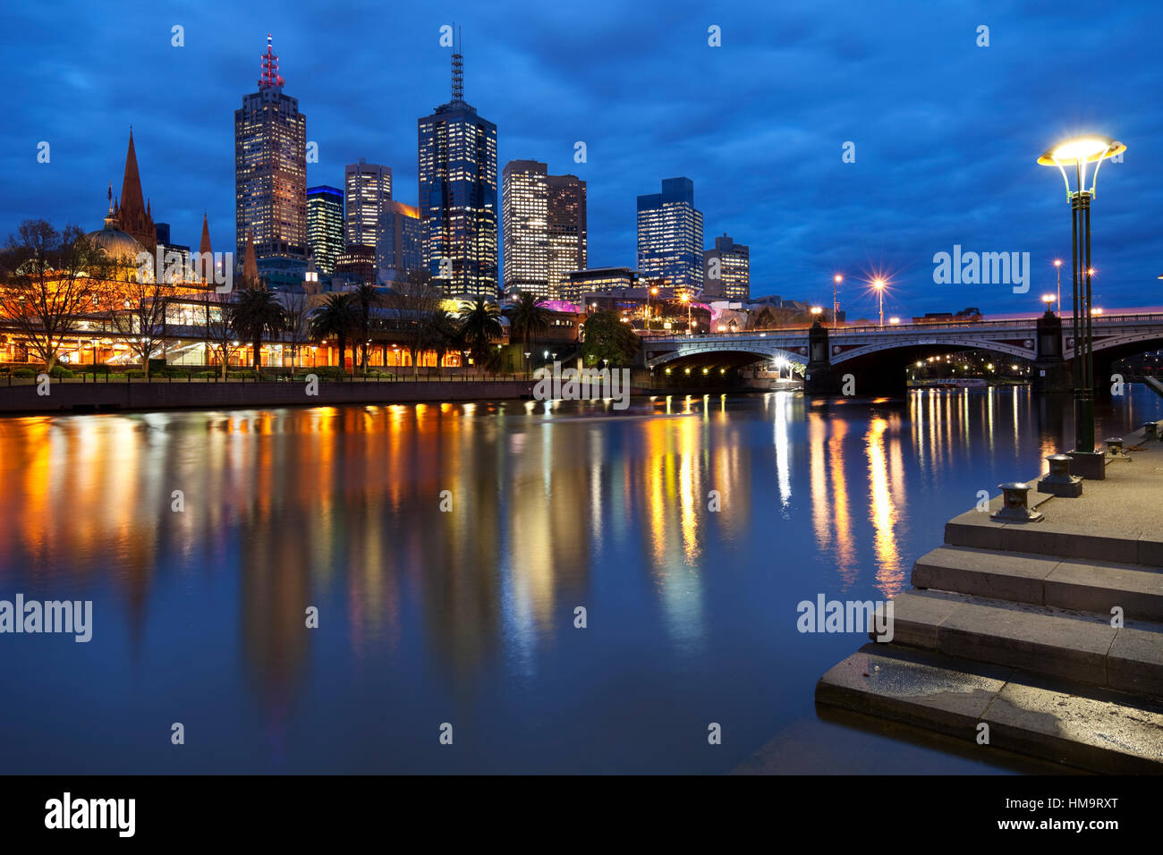 Lo skyline di Melbourne in Australia con la stazione di Flinders Street e i capi da ponte attraverso il fiume Yarra di notte. Foto Stock