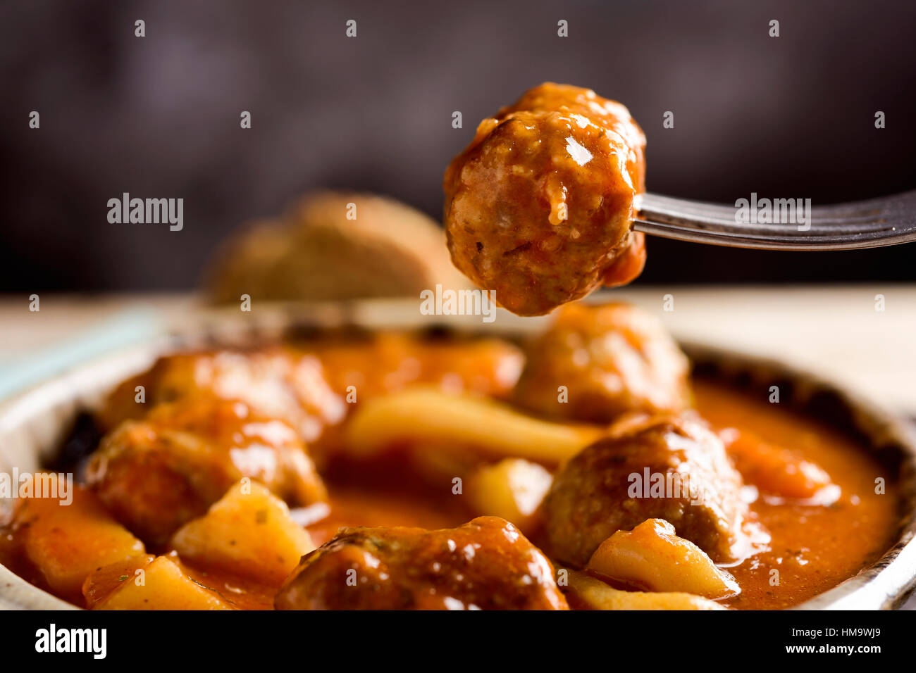 Primo piano di un vaso di terracotta con tipiche albondigas spagnolo con il nero di seppia, polpette con seppie, su una tavola in legno rustico Foto Stock