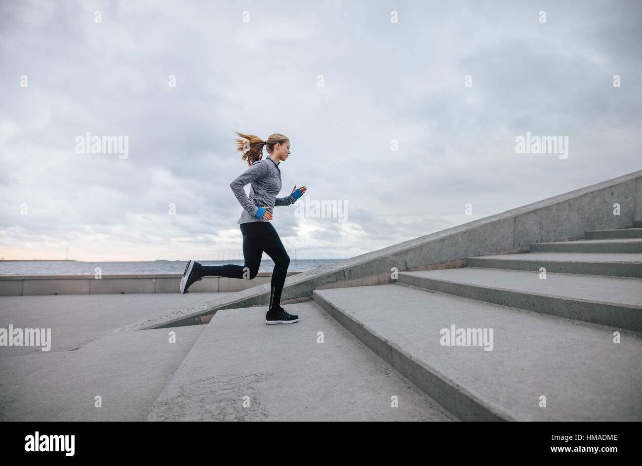Vista laterale colpo di donna fitness in esecuzione su fasi. Femmina atleta runner salendo le scale. Foto Stock