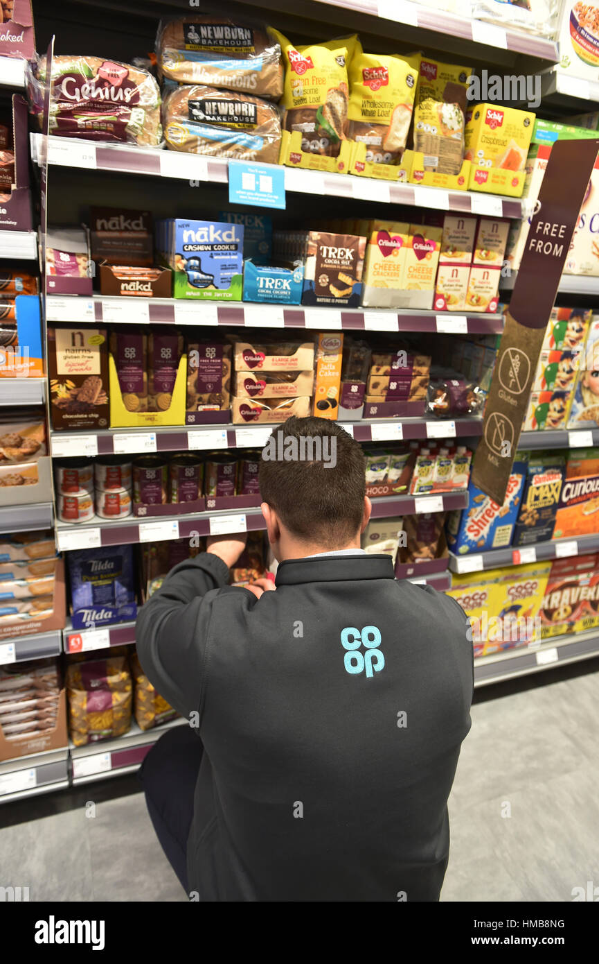 Il personale del negozio ripiano impilaggio in una cooperativa locale store Foto Stock