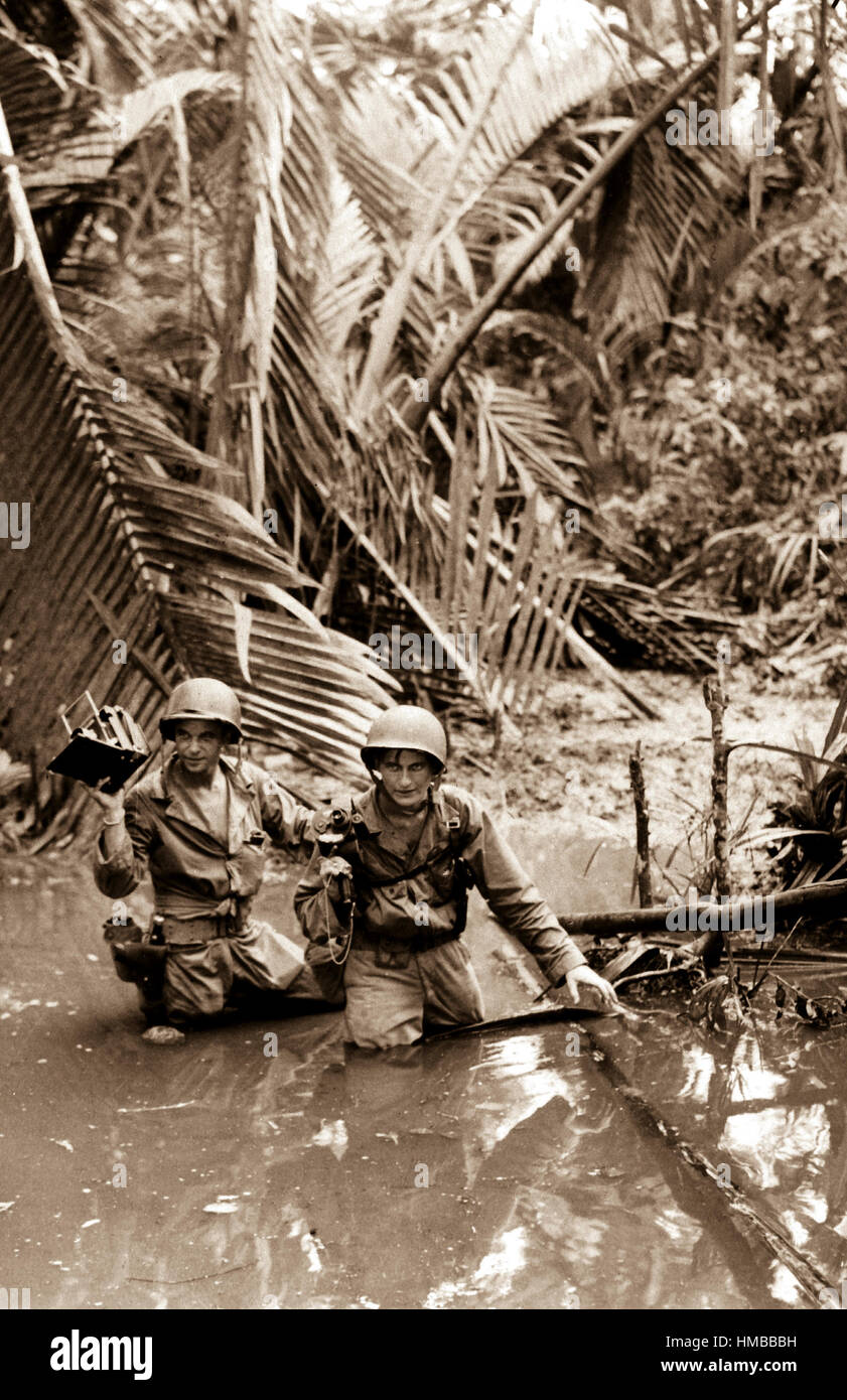 Sgt. Carl Weinke e PFC. Ernest maggiorana, Signal Corps cameramen, guadare attraverso flussi durante la seguente le truppe di fanteria in marcia avanti zona durante l'invasione su una spiaggia in Nuova Guinea. La spiaggia rossa 2, Tanahmerah. Il 22 aprile 1944. T4c. Ernani D'Emidio. (Esercito) Nara il file #: 111-SC-189623 guerra & CONFLITTO PRENOTA #: 868 Foto Stock