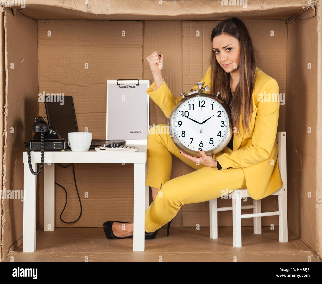 Business donna tenendo un orologio, seduti in un piccolo ufficio Foto Stock