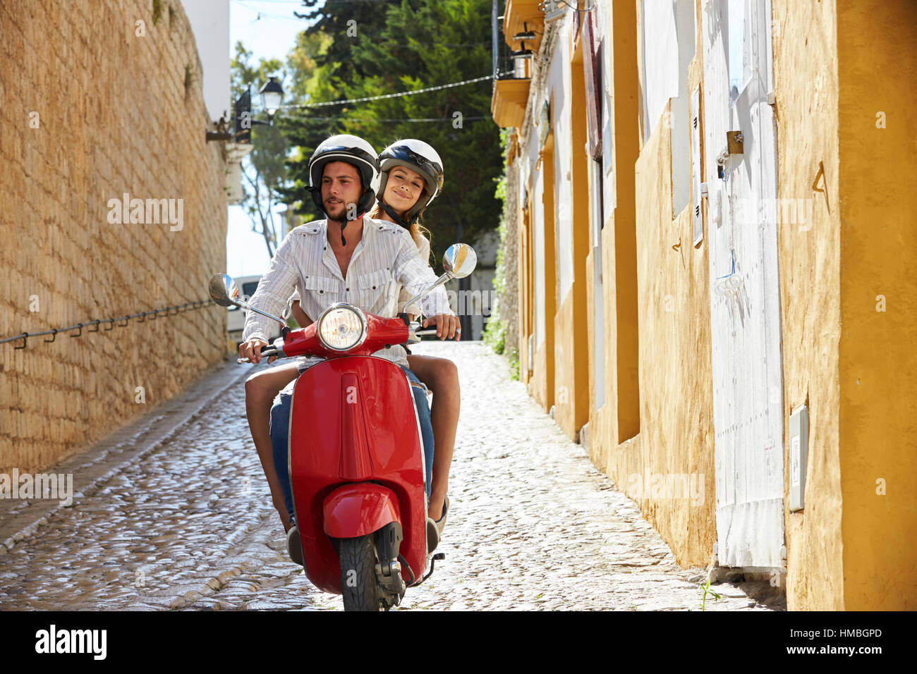 Paio di equitazione scooter a motore nella vecchia strada di Ibiza, vista frontale Foto Stock