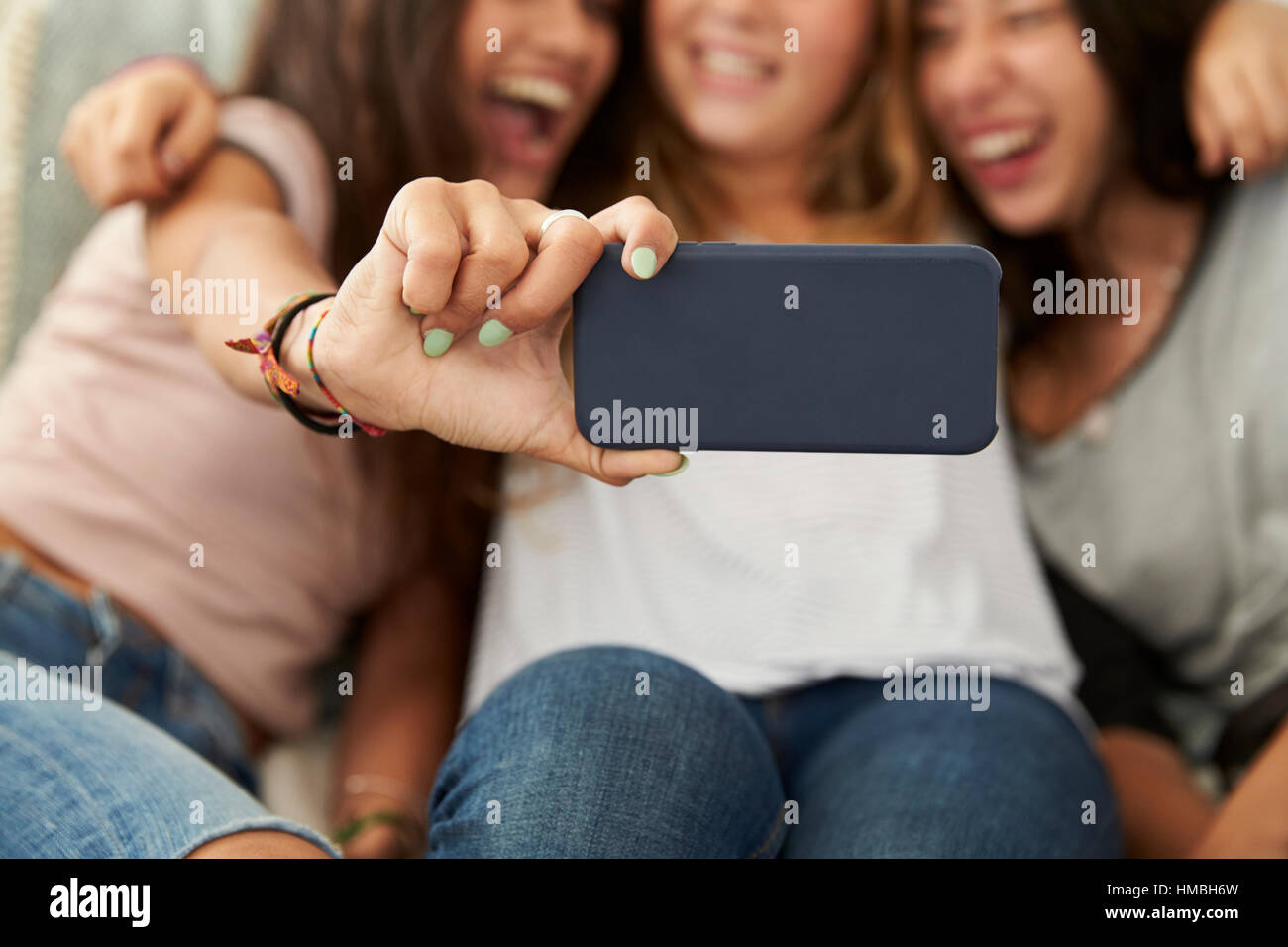 Tre ragazze adolescenti tenendo selfie a casa, concentrarsi sul telefono Foto Stock