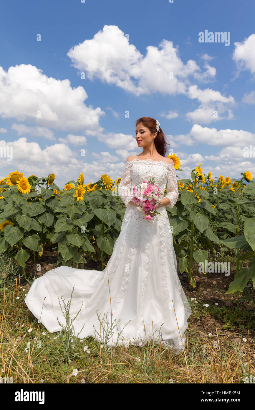 Giovane e bella sposa in posa di un campo di semi di girasole Foto Stock