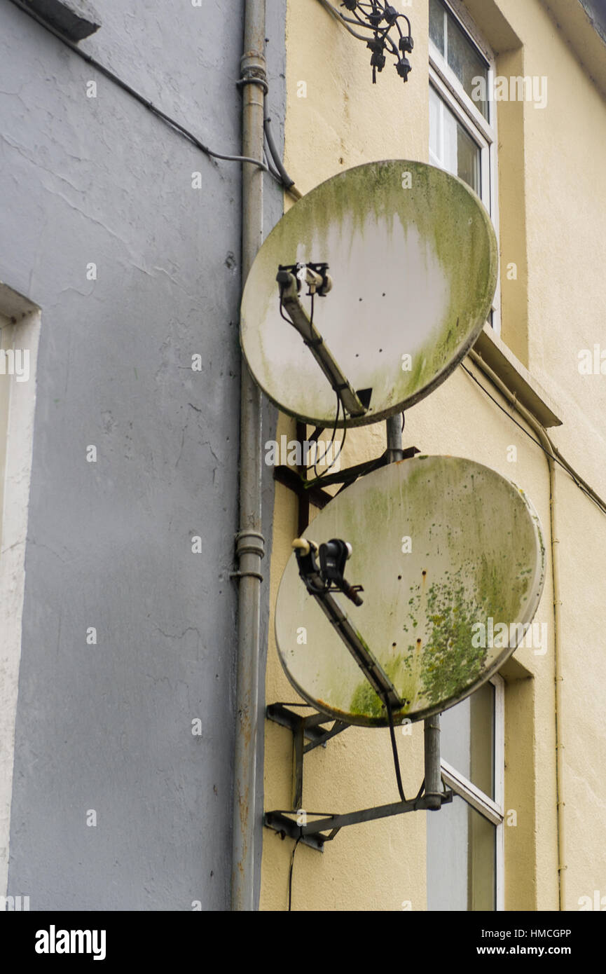 Due vecchi piatti via satellite sulla parete di una proprietà domestica in Irlanda. Foto Stock