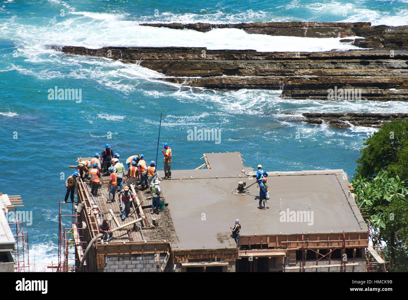 I lavoratori che operano con cemento nel progetto di casa vicino al mare Foto Stock