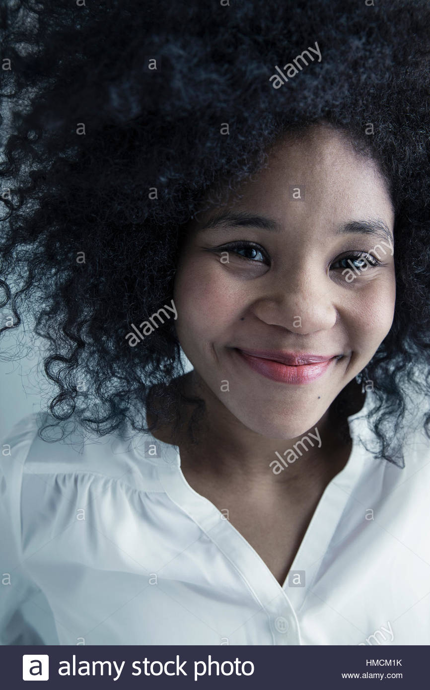 Close up ritratto felice razza mista giovane donna con parentesi nero capelli afro Foto Stock