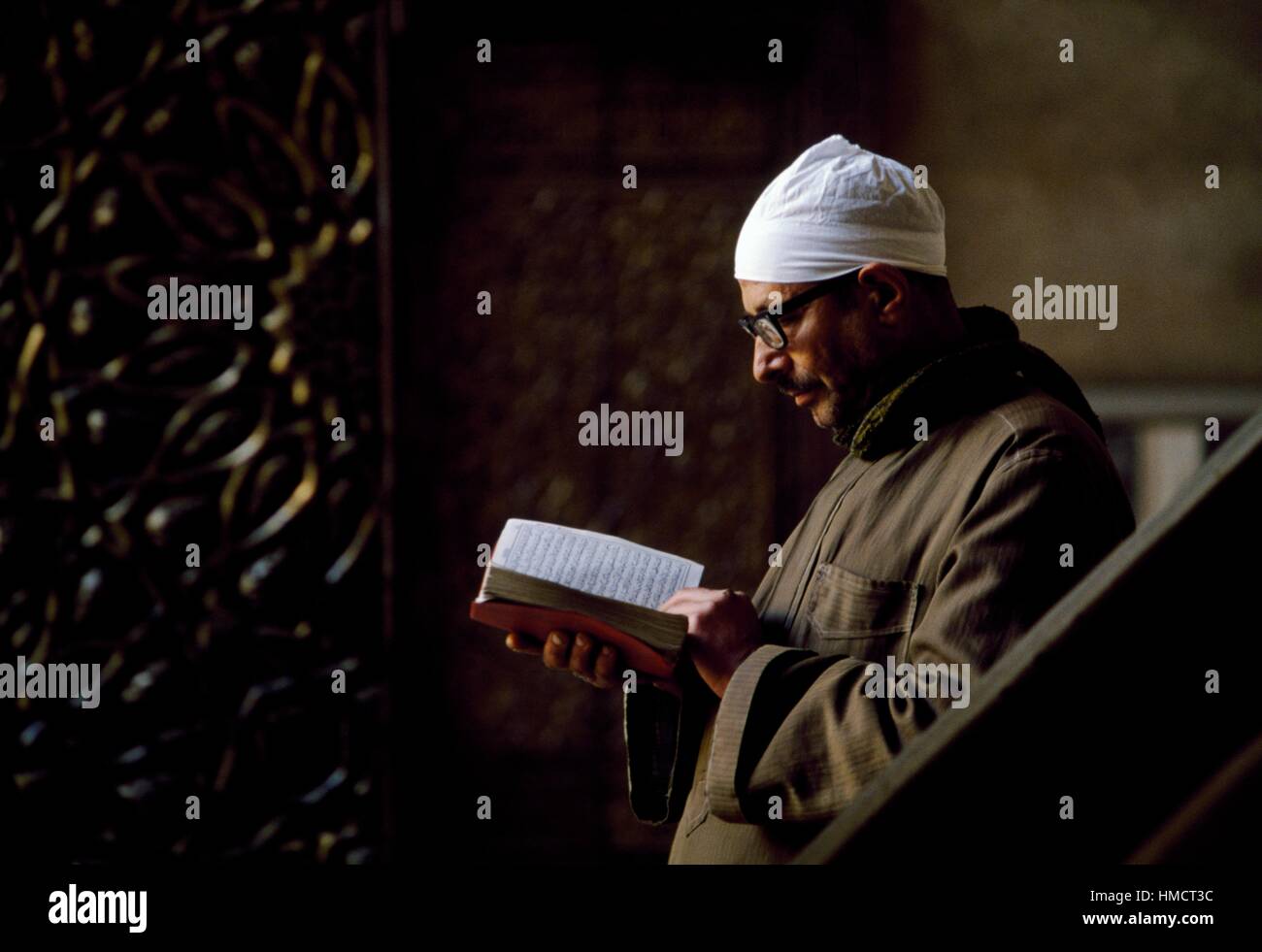 Un uomo la lettura di un testo sacro in Mosque-Madrassa del sultano Hassan, del secolo XIV, Il Cairo, Egitto. Foto Stock
