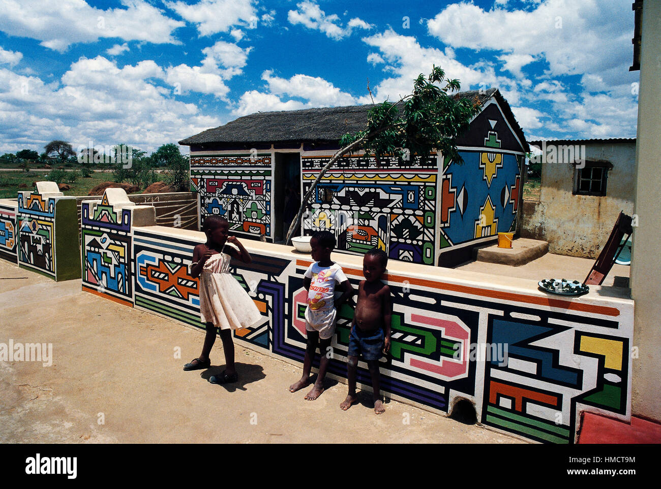 Ndebele i bambini di fronte ad un edificio decorato con dipinti murali nel villaggio, KwaNdebele, Sud Africa. Foto Stock