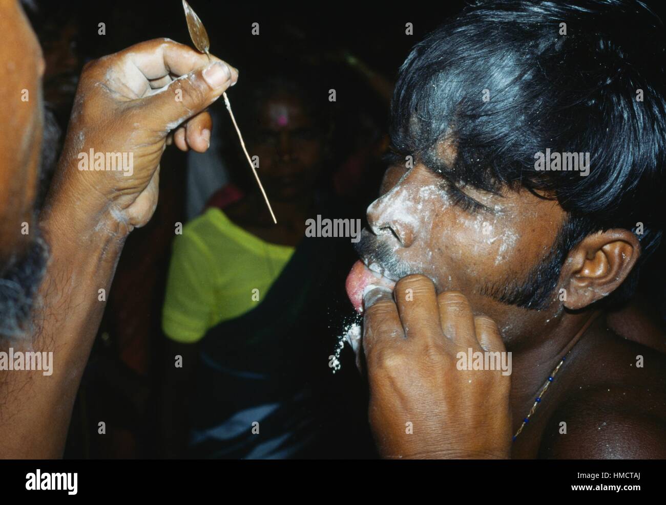 Penitente avente le sue guance e la linguetta forata con un perno da un sacerdote durante la festa del dio Skanda, Kataragama, Sri lanka. Foto Stock
