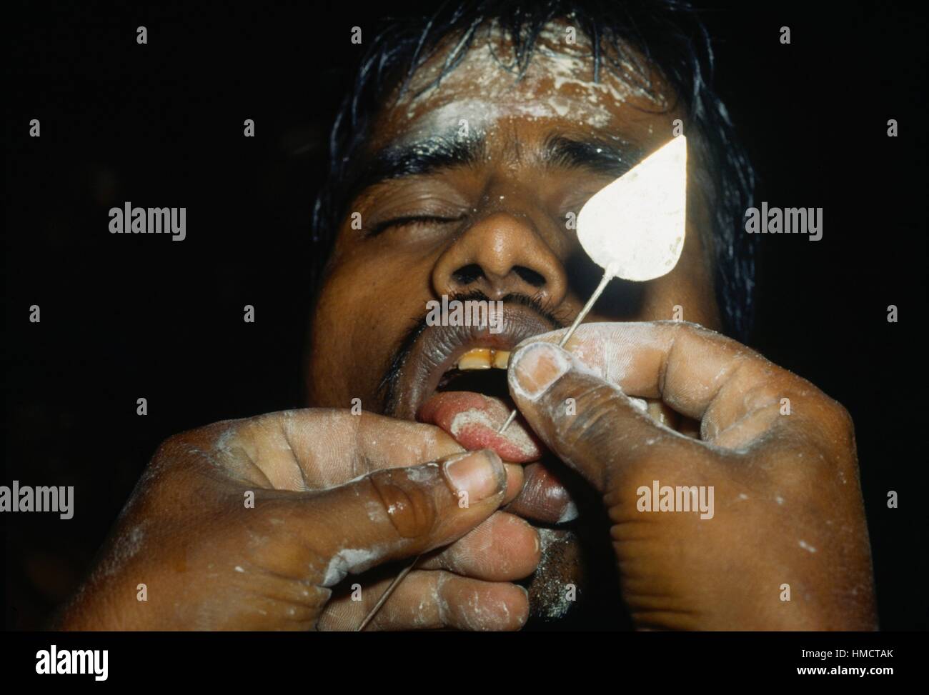 Penitente avente le sue guance e la linguetta forata con un perno da un sacerdote durante la festa del dio Skanda, Kataragama, Sri lanka. Foto Stock