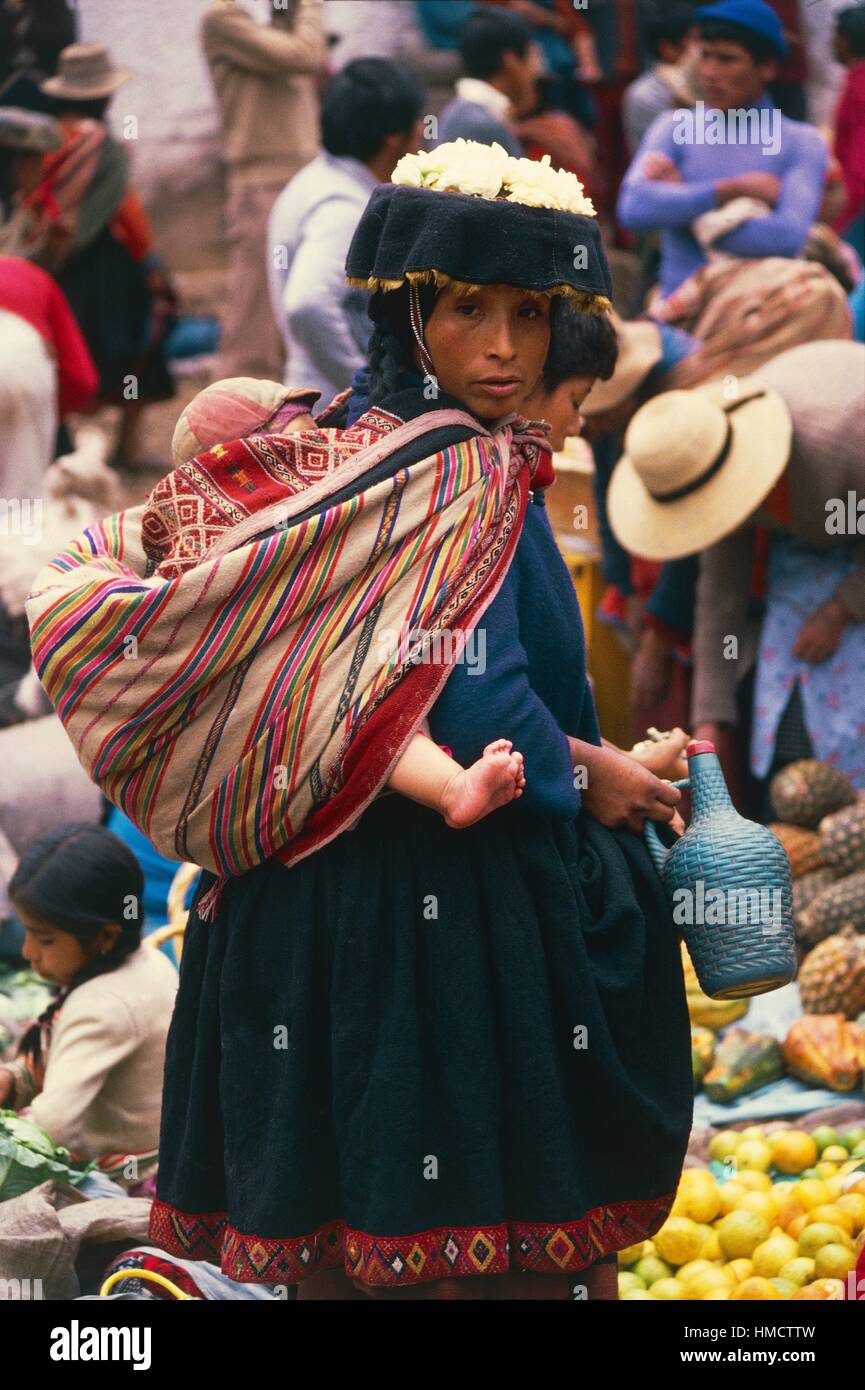Una donna con un bambino in una imbracatura sulla sua schiena, Perù. Foto Stock