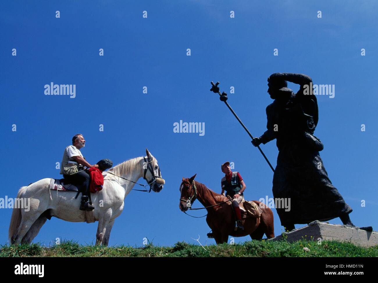 Uomini a cavallo nei pressi di bronzo Statua Pellegrina, vicino a Alto de San Roque, sul cammino di san Giacomo di Compostela (patrimonio mondiale Foto Stock