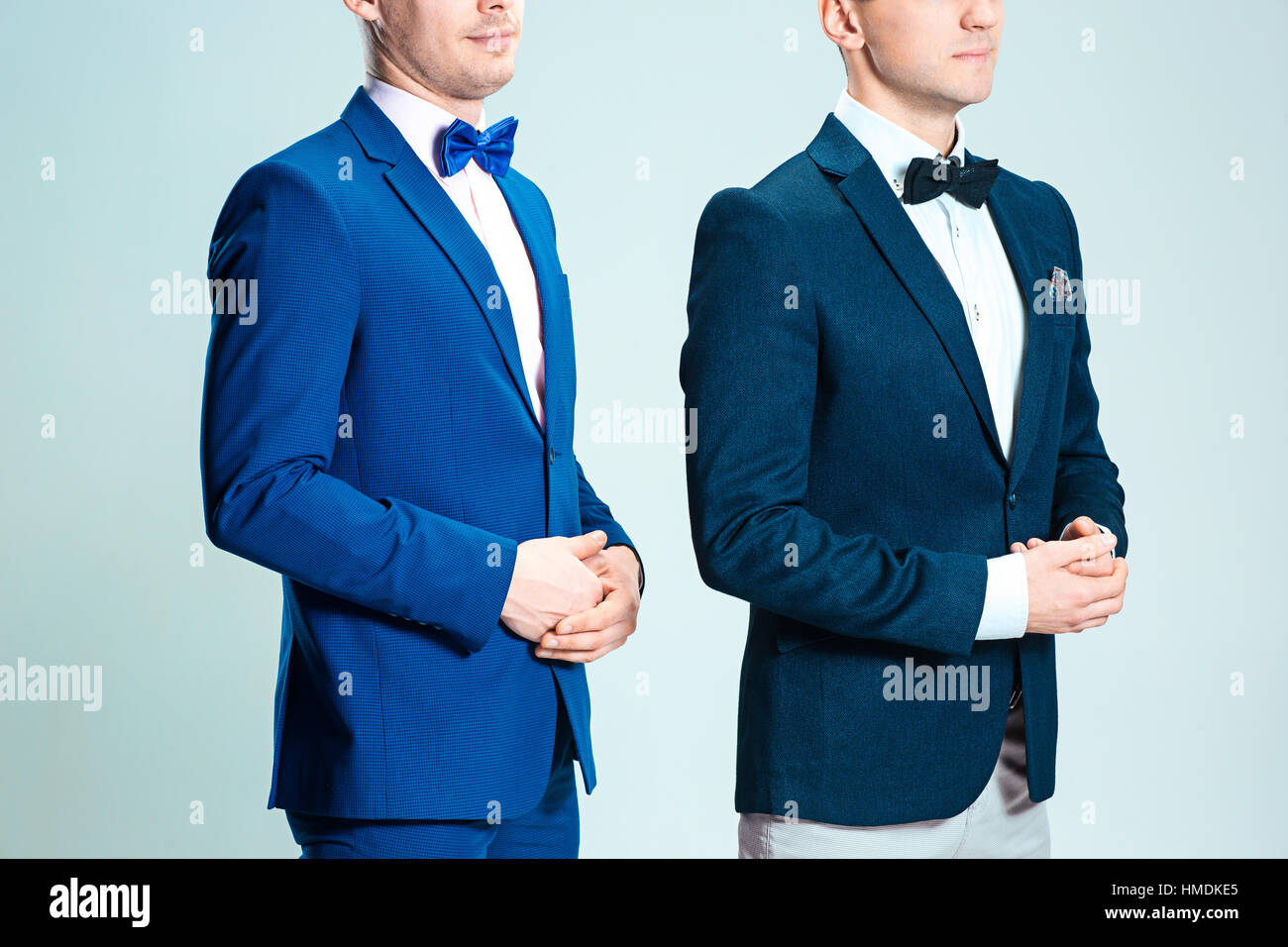 Ritratto di bella ed elegante business uomini che indossano il filtro bow tie e tute su grigio di sfondo per studio Foto Stock