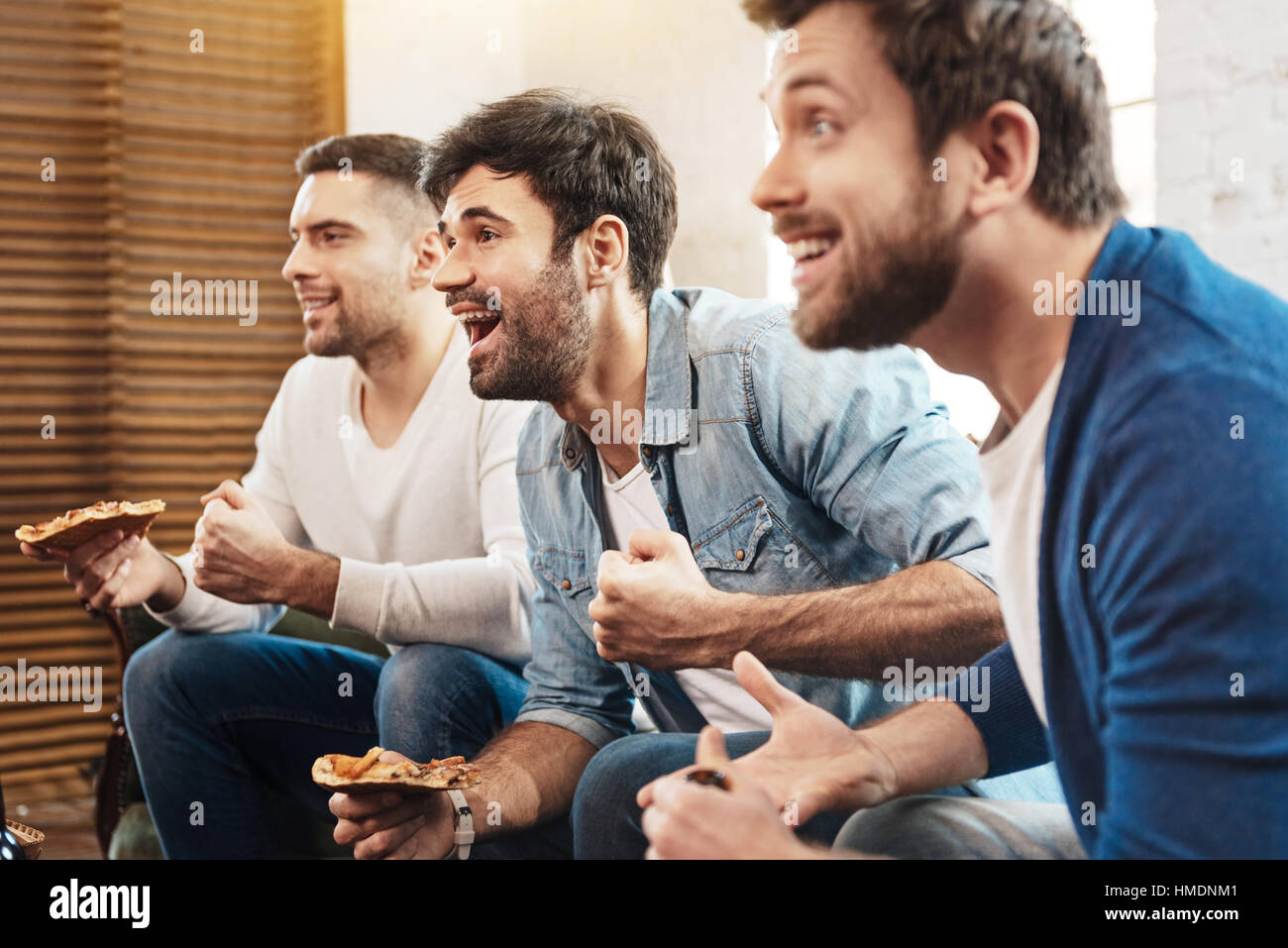 Gioioso positivo amici gustando la loro pizza Foto Stock