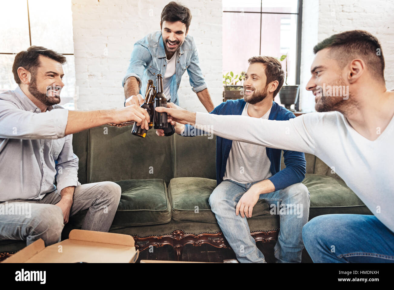 Gioiosa uomini positivo il tintinnio delle bottiglie Foto Stock