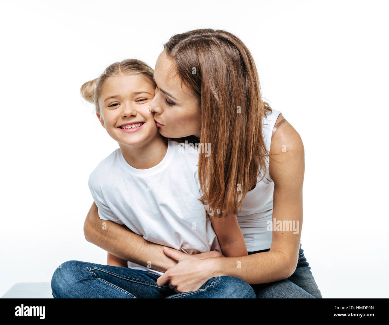 Madre abbracciando e baciando figlia sorridente Foto Stock