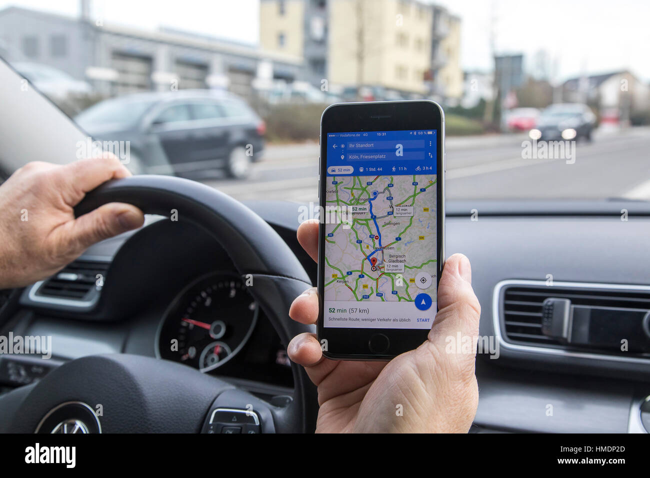 Un autista è utilizzando un telefono cellulare, smartphone durante la guida di un automobile, app di navigazione, Foto Stock