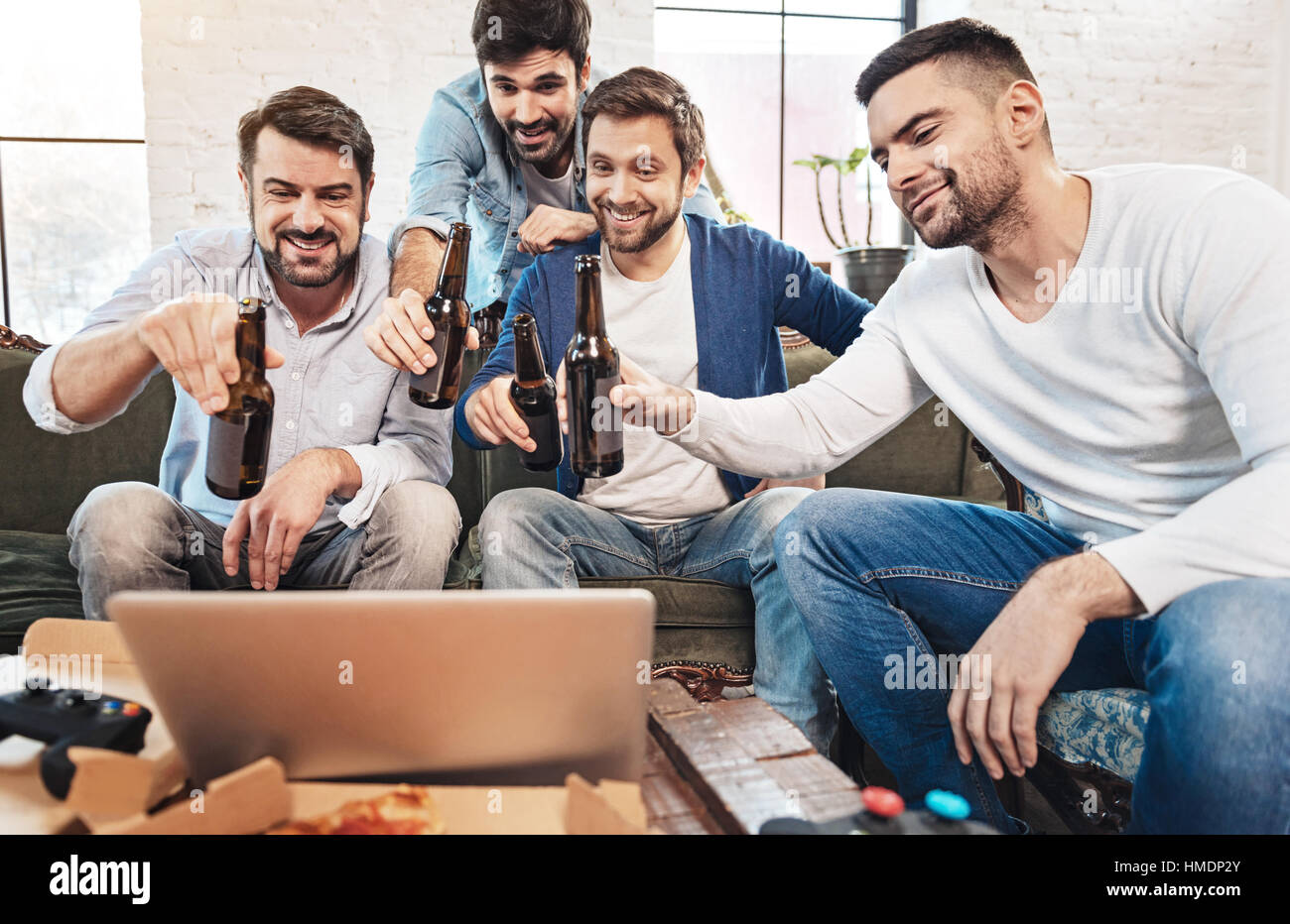 Felice allegro uomini di bere birra con i loro amici online Foto Stock
