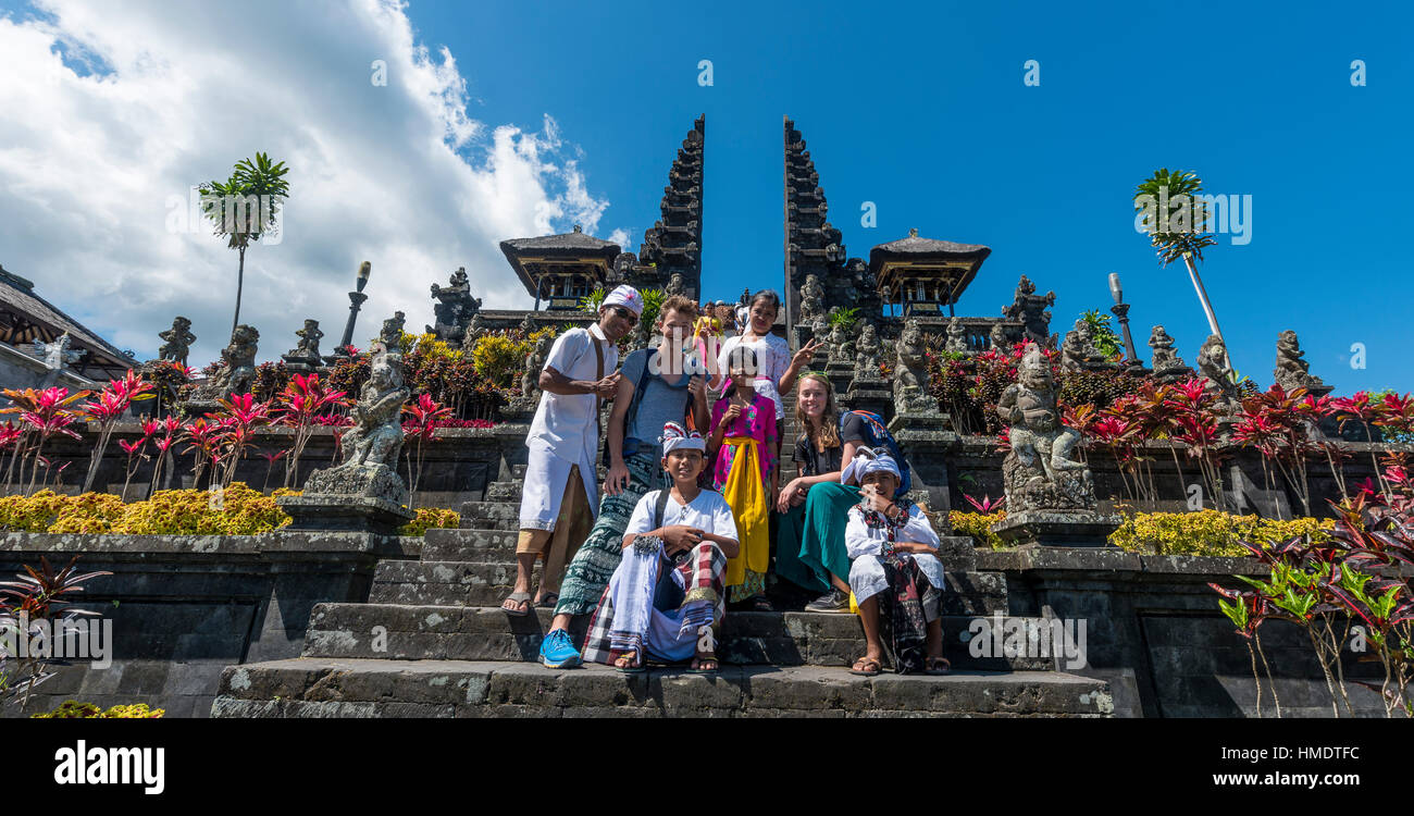 Devota ponendo Balinese con turisti europei, split gate, Candi bentar, Tempio madre Besakih, Pura Agung Penetaran Besakih Foto Stock