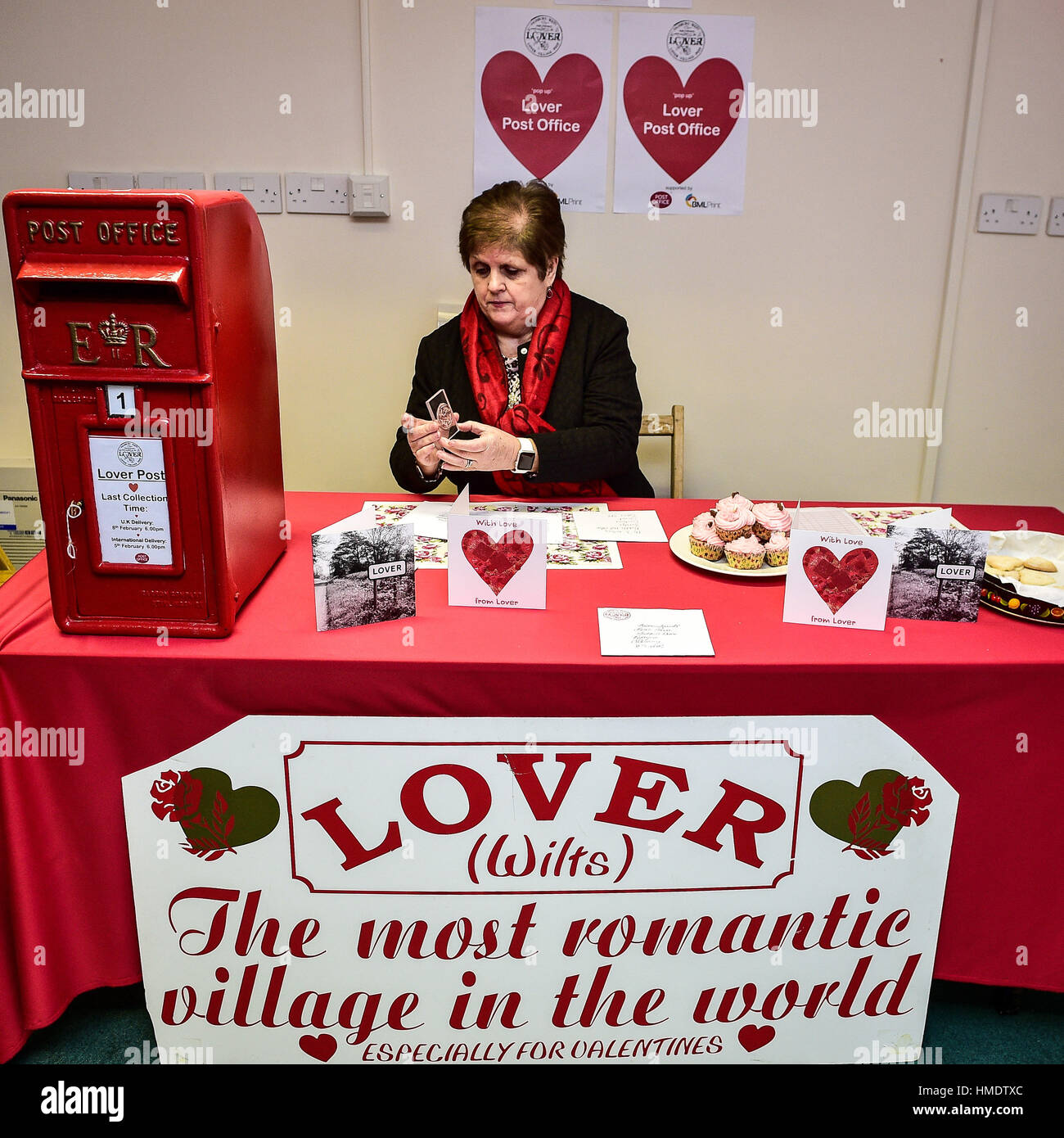 Capo Postmistress Lynda Cooper francobolli schede San Valentino nella finestra pop-up post office nel villaggio di Amante, nuova foresta dove i residenti hanno lanciato un il giorno di San Valentino post service, consentendo ai romantici in tutto il mondo per inviare una scheda da Wiltshire village. Foto Stock