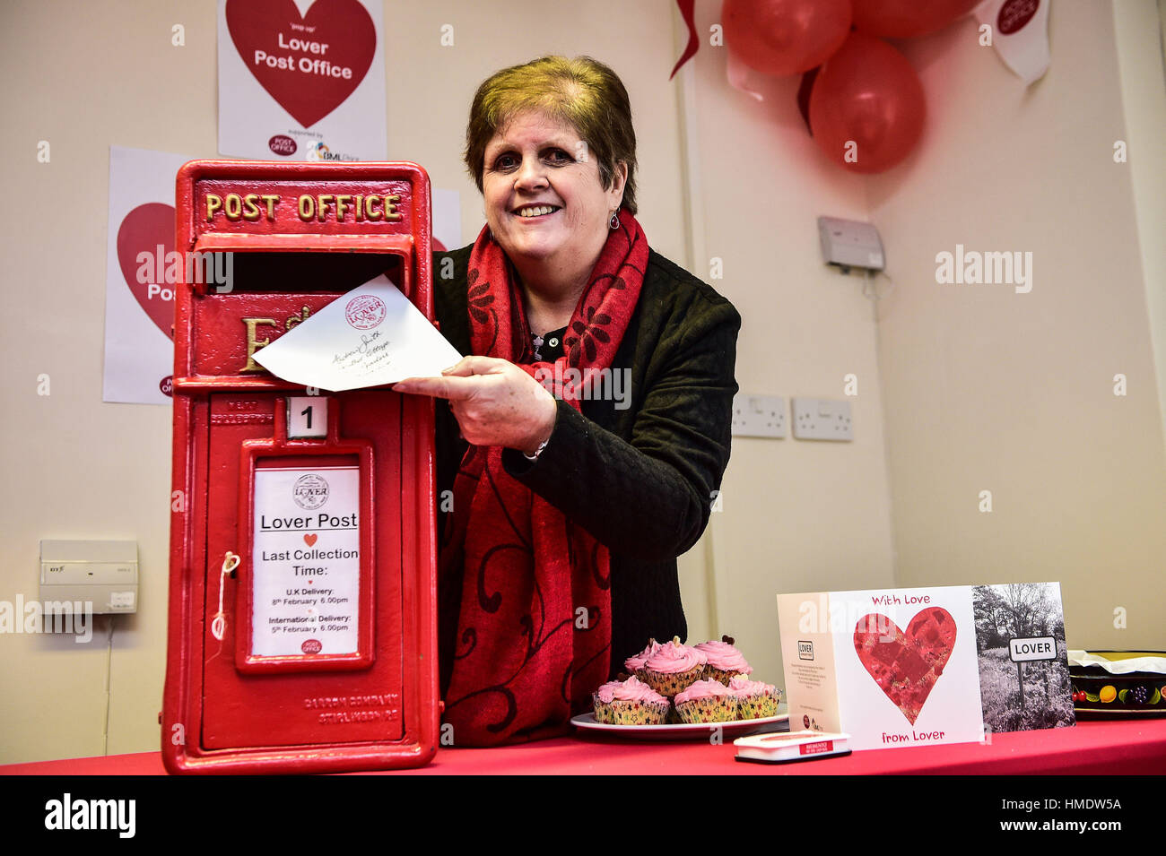 Capo Postmistress Lynda Cooper posts un scheda di San Valentino nella finestra pop-up post office nel villaggio di Amante, nuova foresta dove i residenti hanno lanciato un il giorno di San Valentino post service, consentendo ai romantici in tutto il mondo per inviare una scheda da Wiltshire village. Foto Stock