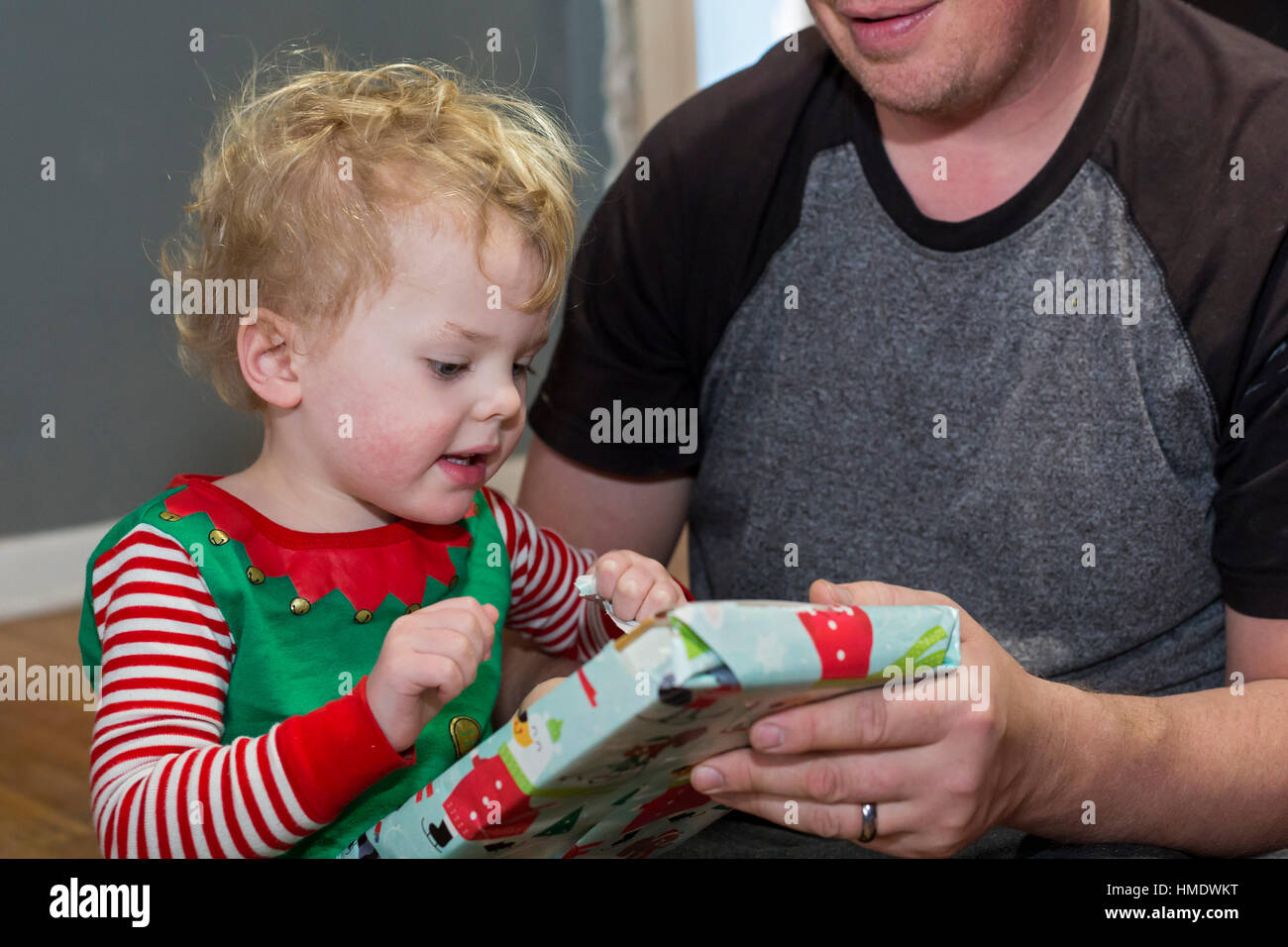 Denver, Colorado - Adam Hjermstad Jr., 2 1/2, apre un regalo di Natale tenuto da suo padre, Adam Hjermstad Sr. Foto Stock