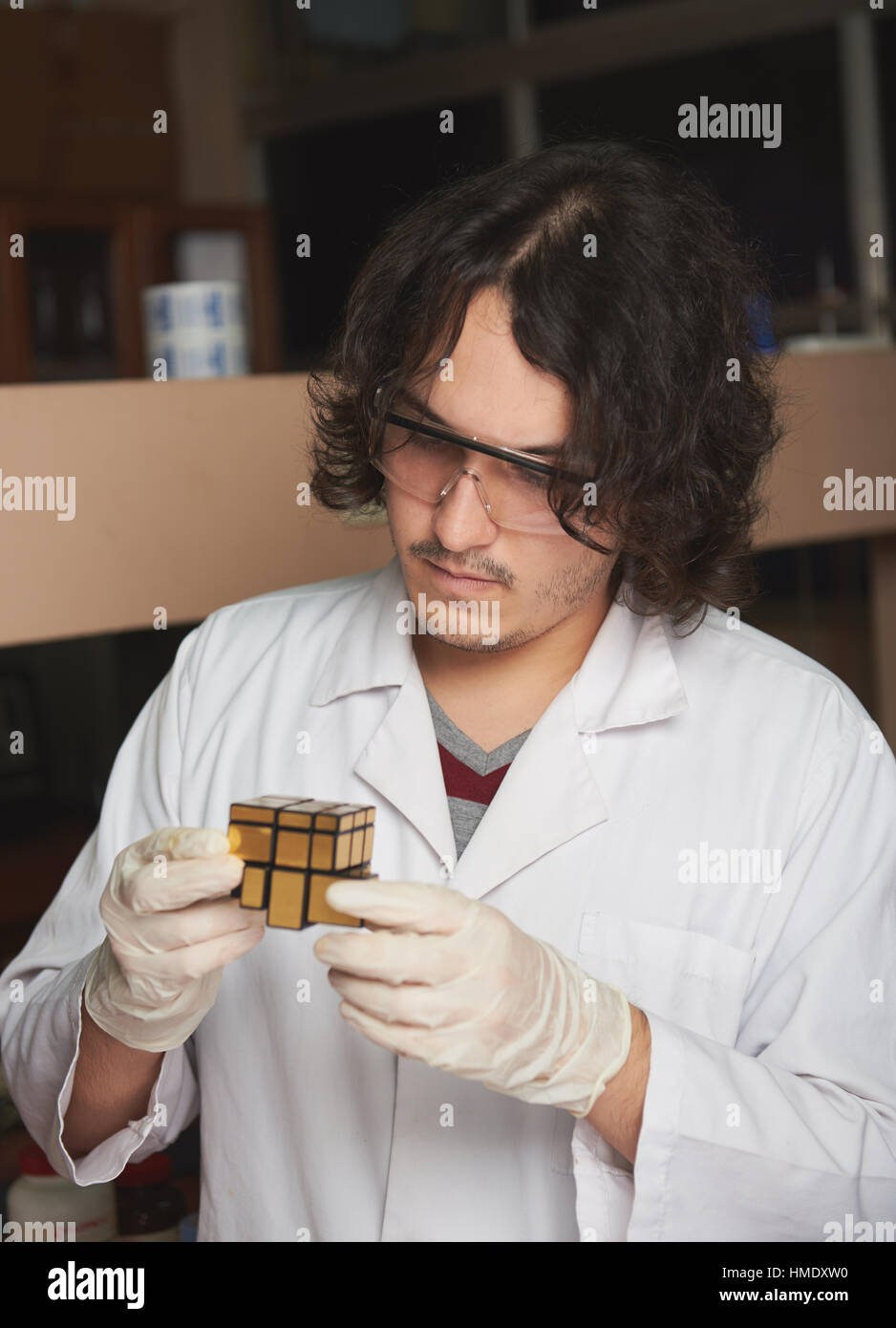 Giovane scienziato risolvere un cubo di Rubik in un laboratorio Foto Stock
