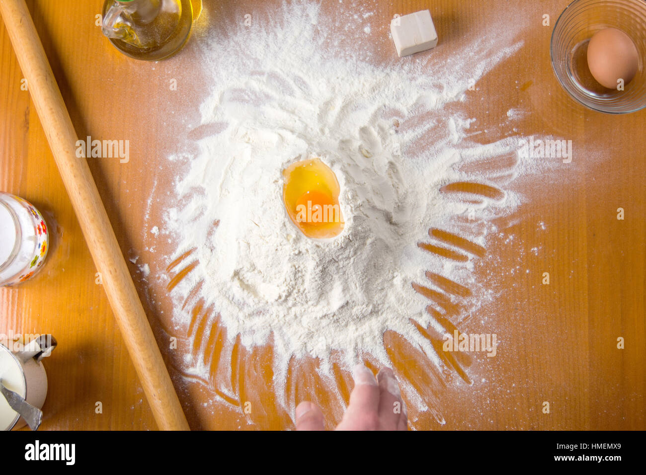 Uovo rotto sulla pila di farina con strumenti di cottura Foto Stock