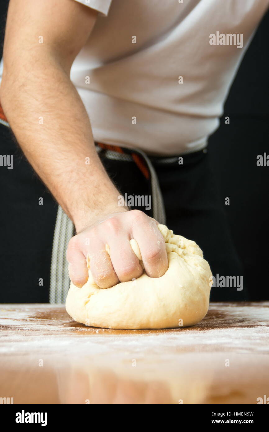 Voce maschile baker punzonatura di impasto dal tavolo della cucina Foto Stock