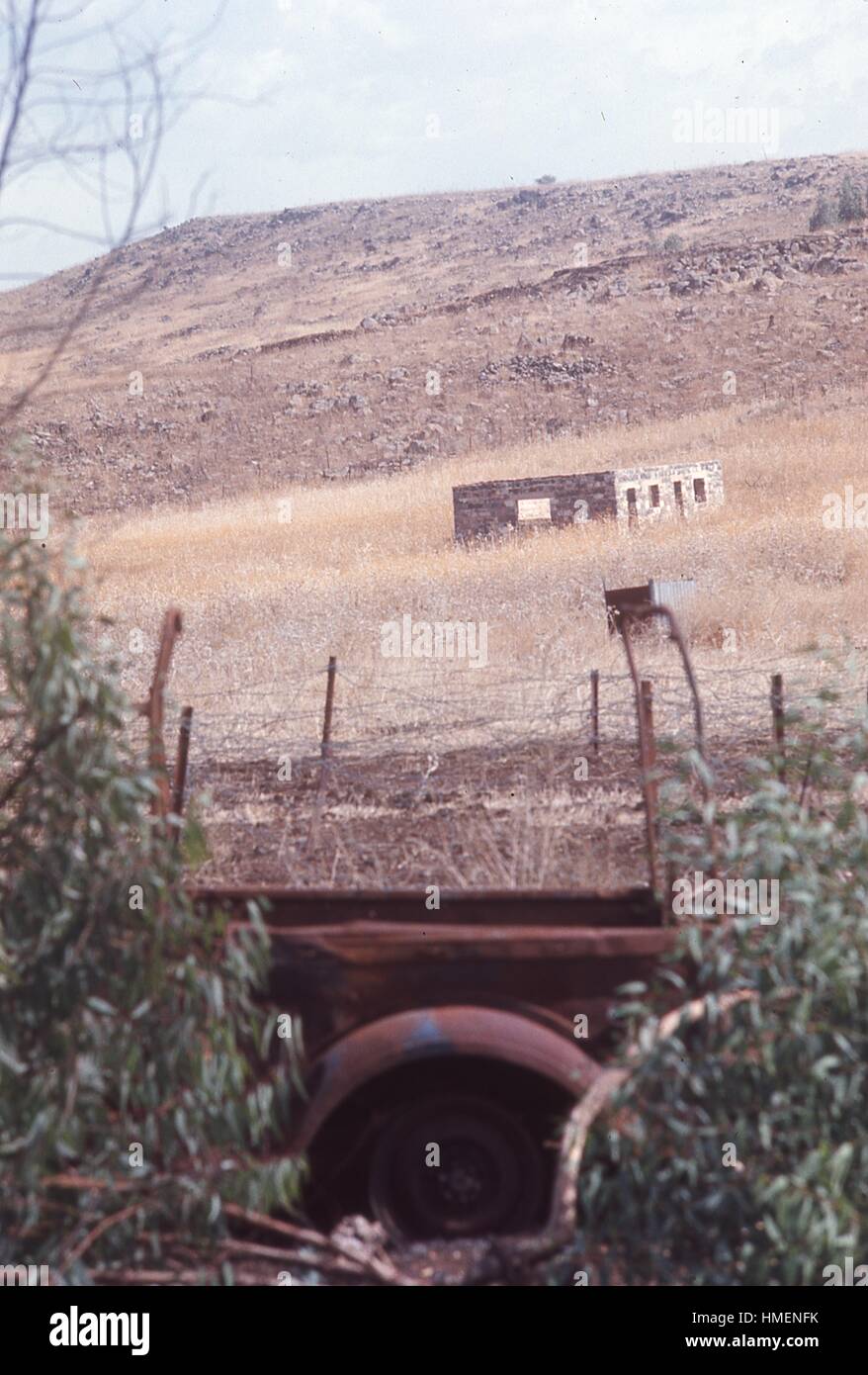 Vista del paesaggio di bruciato un veicolo militare in primo piano una struttura in pietra nel piano medio e colline sullo sfondo, in alture del Golan al di fuori della città di Quneitra, Siria, lungo la frontiera con Israele, novembre 1967. (Foto dalla collezione di Morse/Gado/Getty Images). Foto Stock