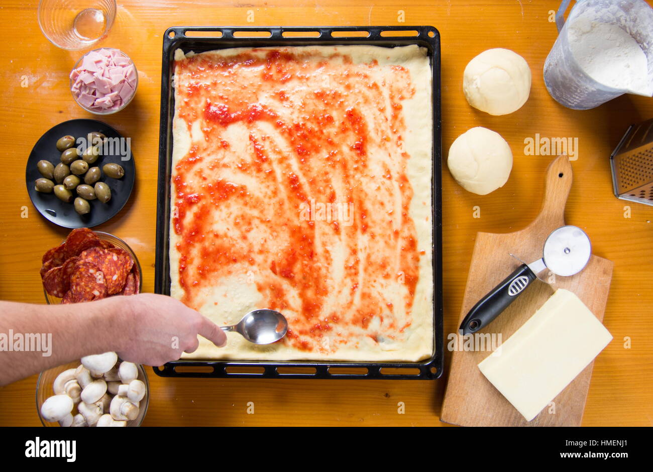Uomo di mettere la salsa di pomodoro sulle materie di base per pizza Foto Stock