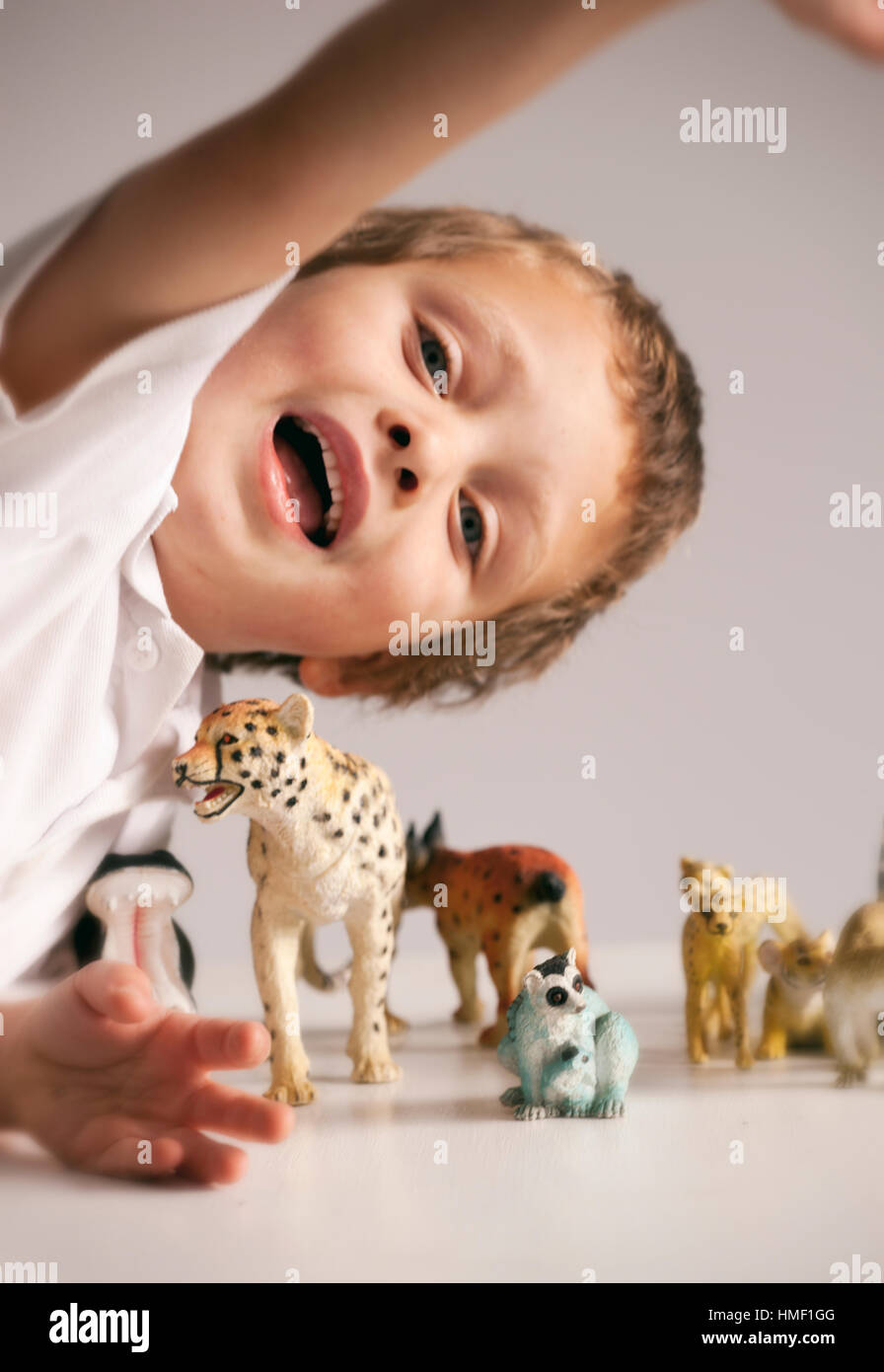 A quattro anni di vecchio ragazzo gioca con assortimento di animali modello su un tavolo Foto Stock
