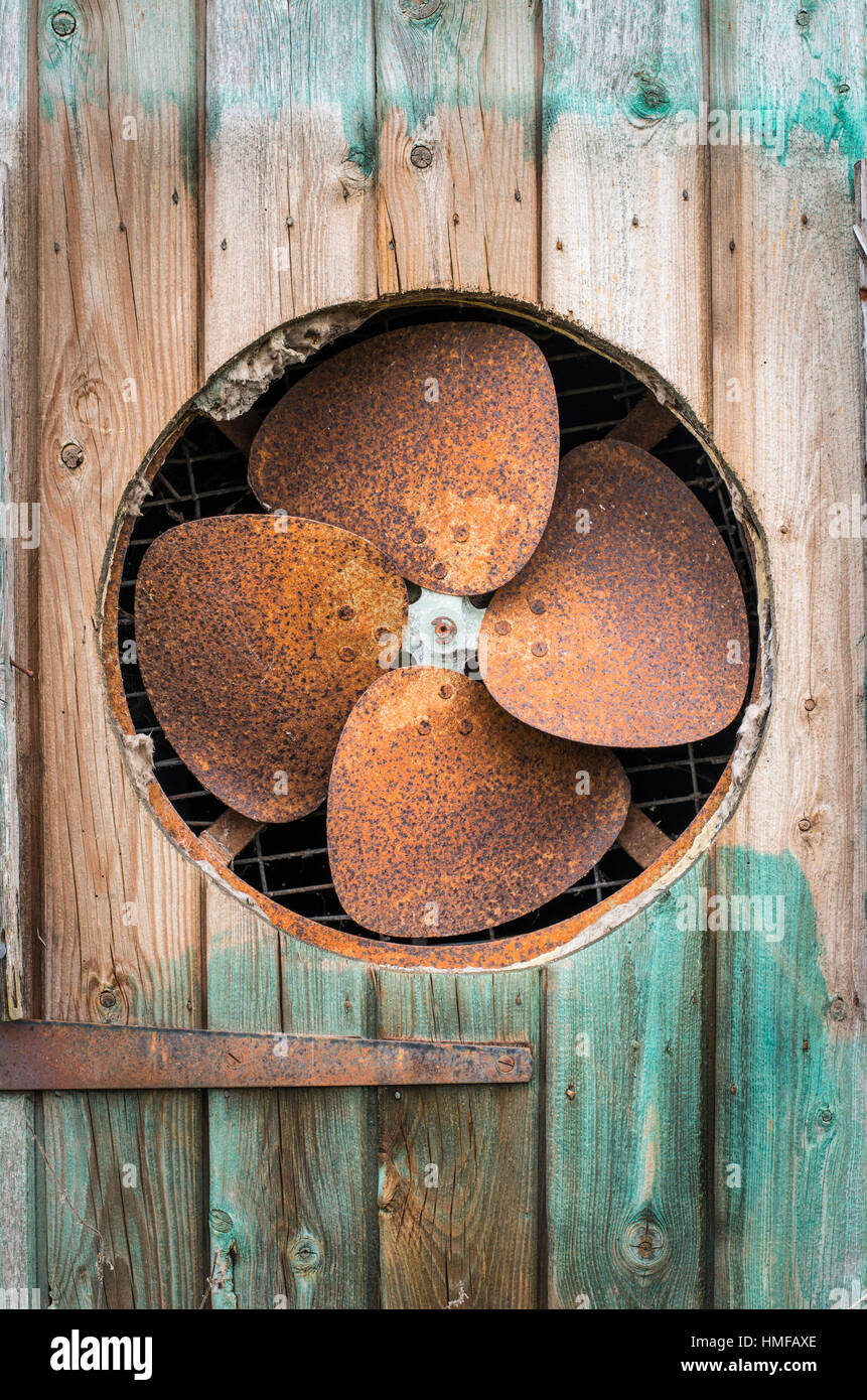 Vecchio arrugginito ventola estrattore in una porta di legno Foto Stock