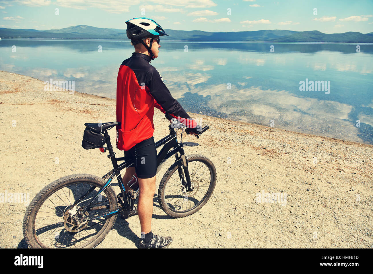 L'uomo con la bici in un lago di montagna Foto Stock