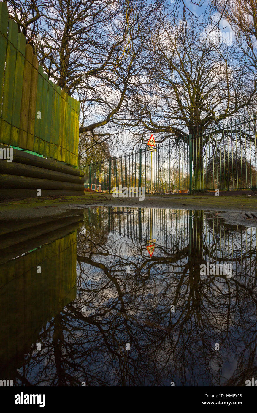 Un percorso lungo una linea di recinzione sulla sinistra con un cartello di avvertimento in background prese con qualche immagine in riflessione. Foto Stock