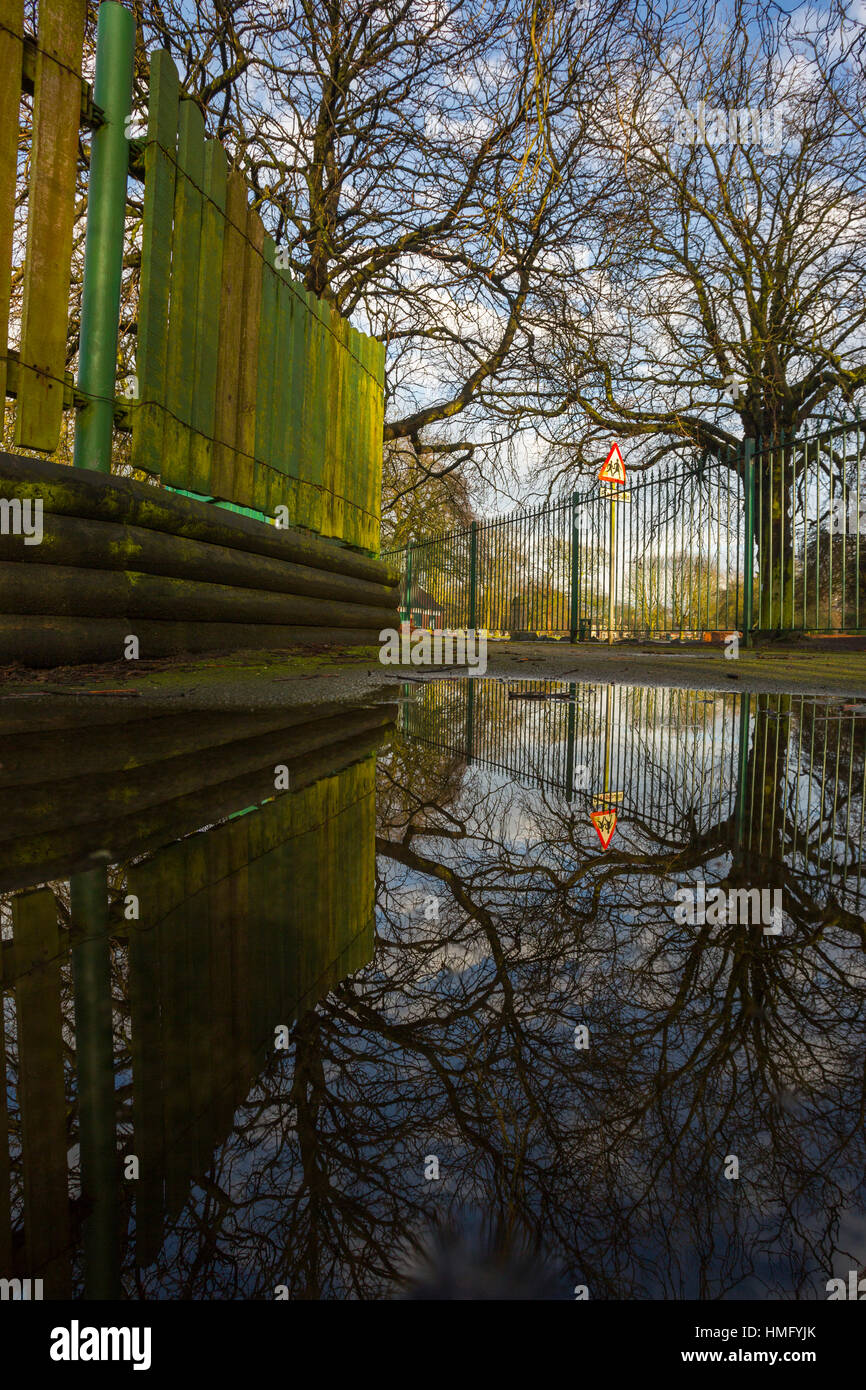 Un percorso lungo una linea di recinzione sulla sinistra con un cartello di avvertimento in background prese con qualche immagine in riflessione. Foto Stock