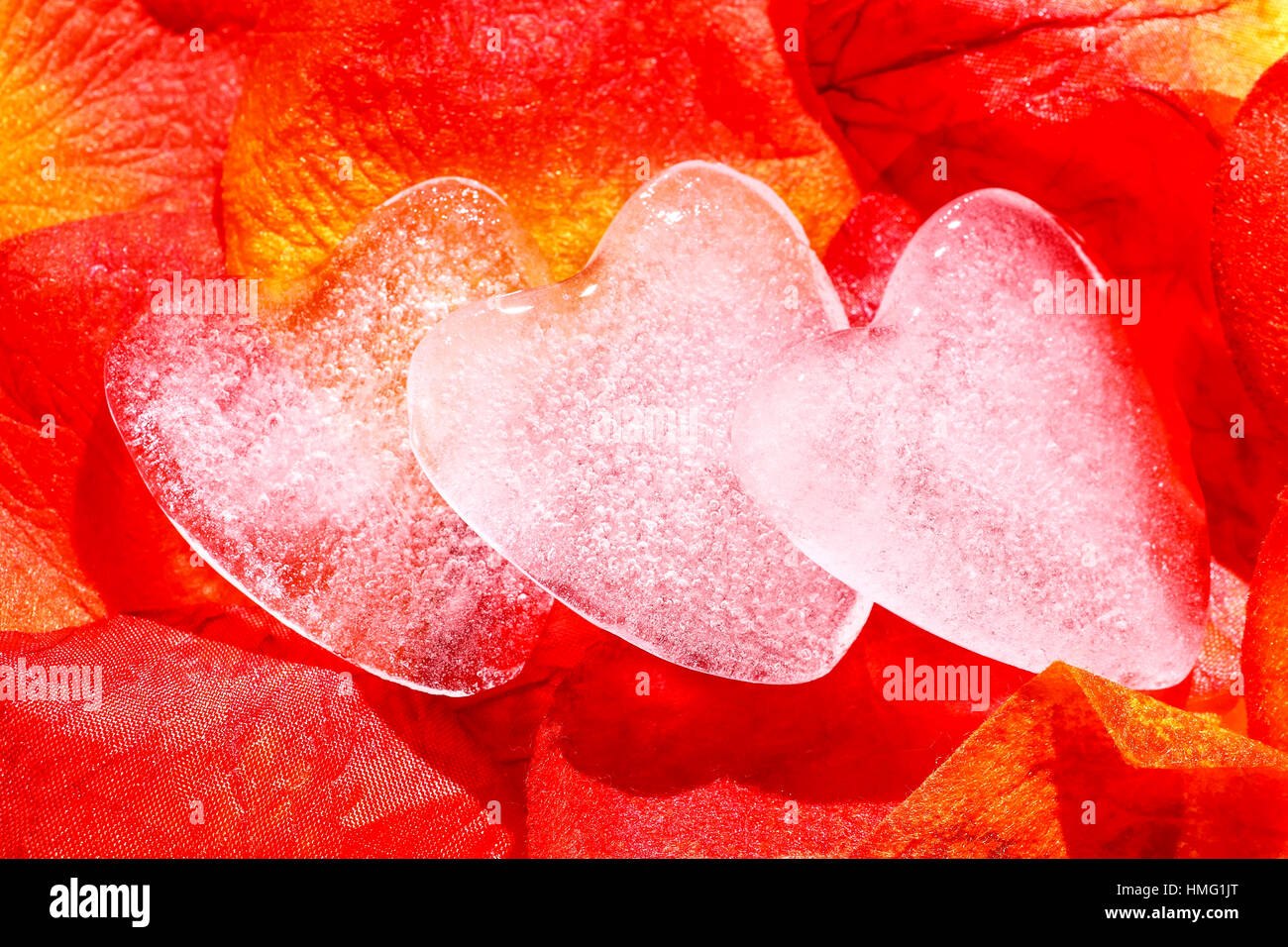 Romantico a forma di ghiaccio cuori isolati su artificiale petali di colore rosso Foto Stock