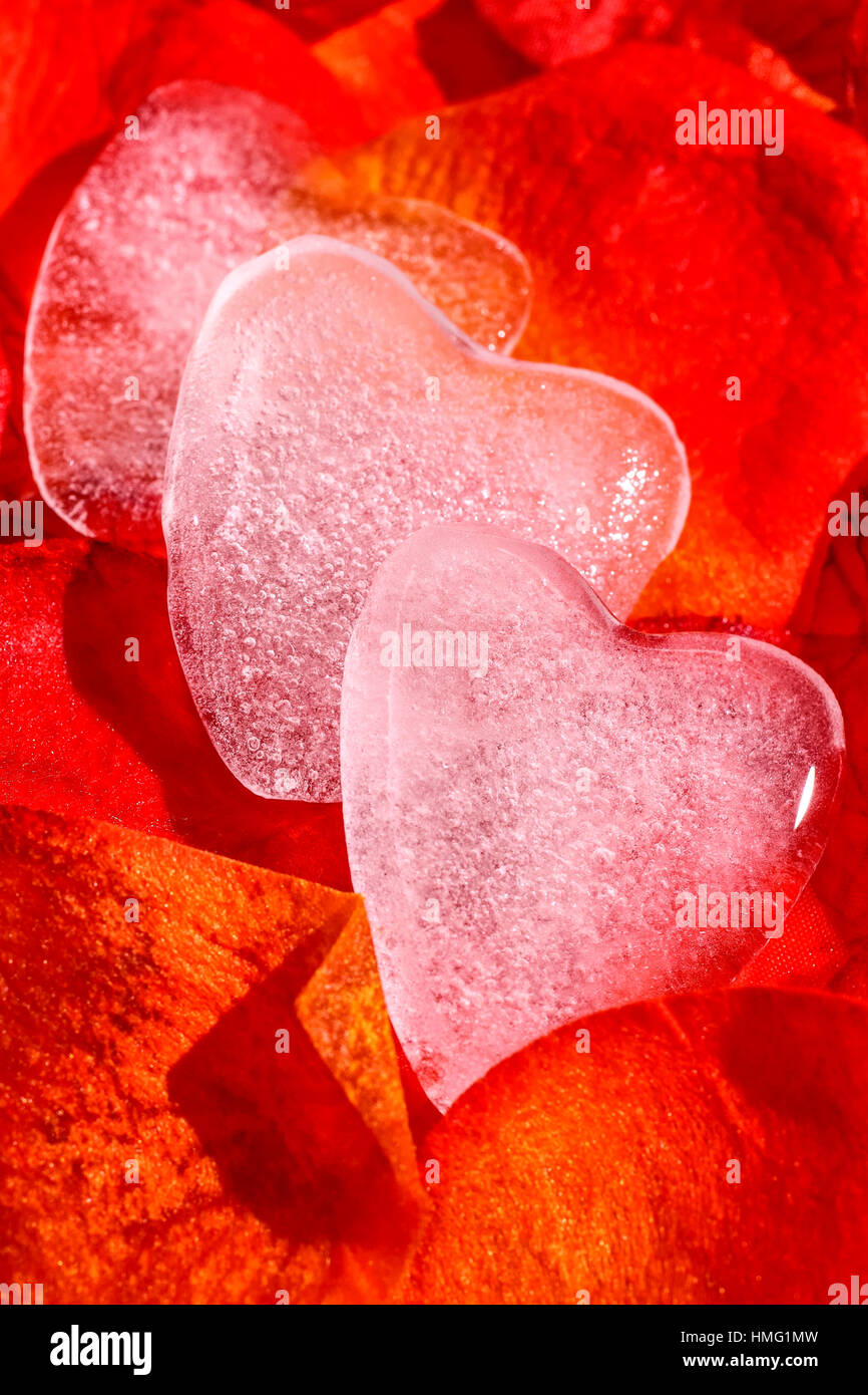 Romantico a forma di ghiaccio cuori isolati su artificiale petali di colore rosso Foto Stock