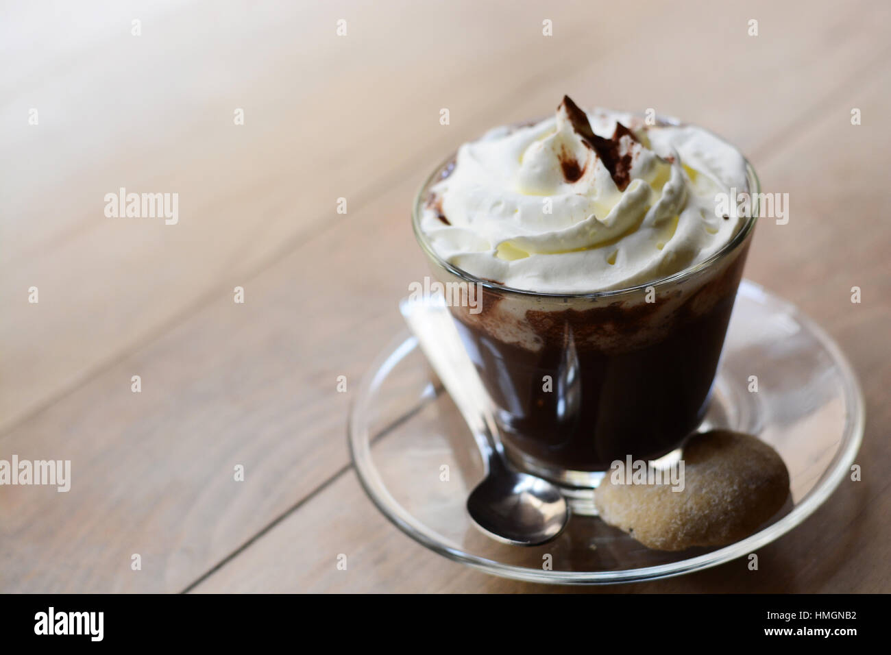Close-up di una tazza di cioccolata calda con panna montata e cacao in polvere sul tavolo di legno Foto Stock Close-up di una tazza di cioccolata calda con panna montata e cacao in polvere sul tavolo di legno Foto Stock