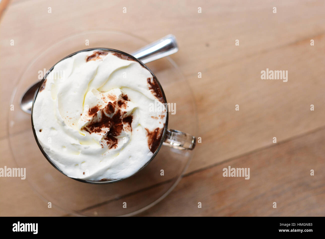 Close-up di una tazza di cioccolata calda con panna montata e cacao in polvere sul tavolo di legno Foto Stock Close-up di una tazza di cioccolata calda con panna montata e cacao in polvere sul tavolo di legno Foto Stock