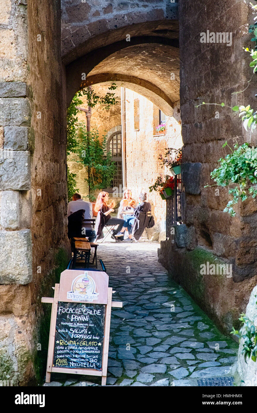I turisti rilassante in un bistro all'aperto, Civita di Bagnoregio, Umbria, Italia Foto Stock