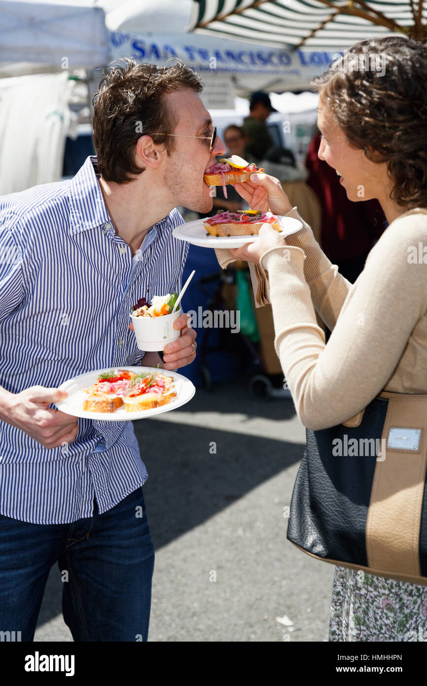 Giovane Condividendo cibo ad un festival di strada di San Francisco, California Foto Stock