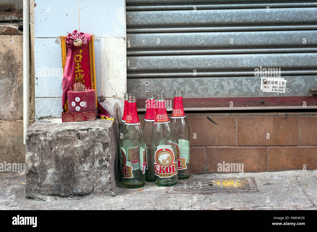 Piccolo Santuario per la messa a terra Dio Tu Di e bottiglie di birra su Hong Kong street. Il testo recita "la porta di terra Dio". Foto Stock