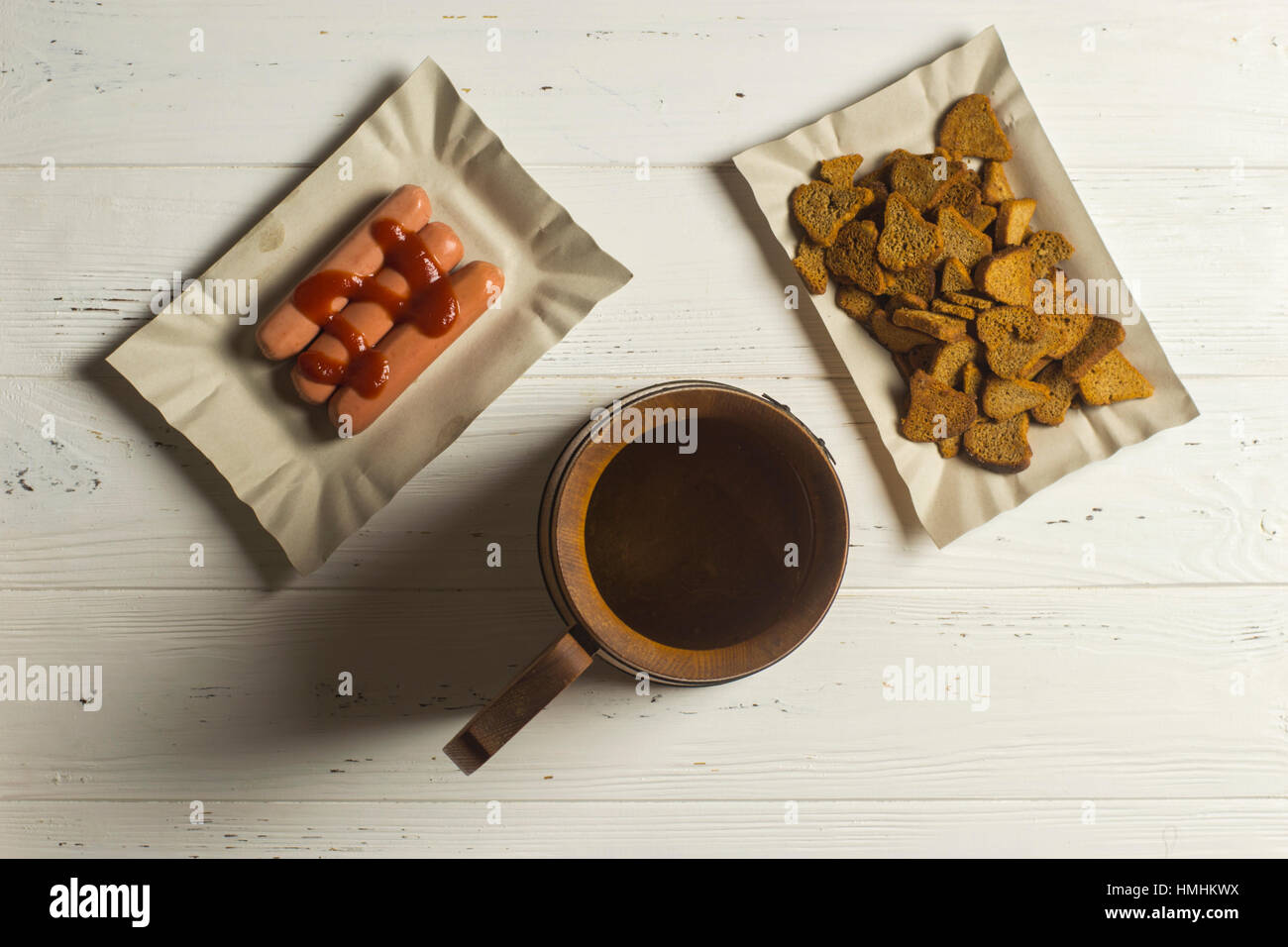 Boccale di birra, salsicce e pane secco su sfondo di legno Foto Stock